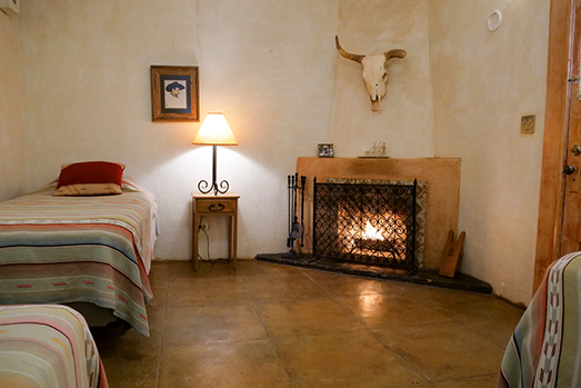 Fireplace and twin bed in a guest room at Rancho de la Osa.